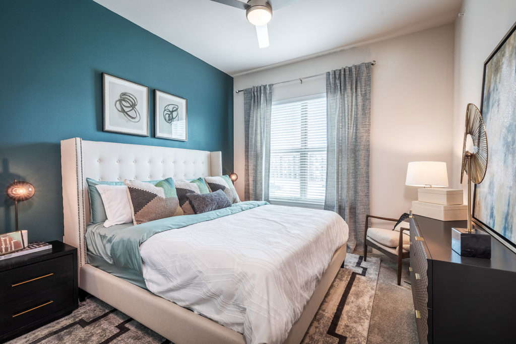 Bedroom with ceiling fan, carpet flooring, accent walls, lamps, and modern decor