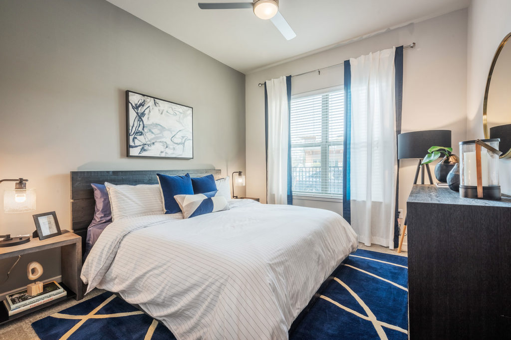 Bedroom with king size bed, large windows for natural light, contemporary dual lamps and nightstands, plush rug and carpeting.