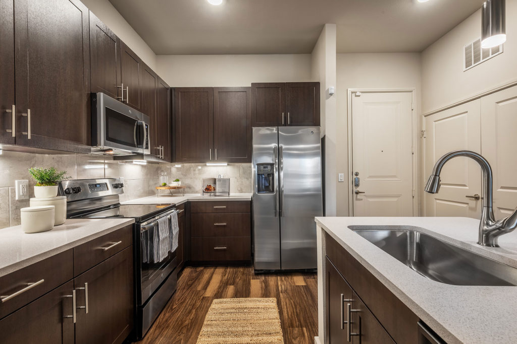 Kitchen area with island and single sink, steel appliances, and wood-style flooring
